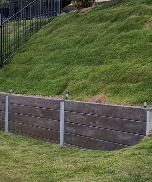 Concrete sleeper wall with garden lights below a turfed slope