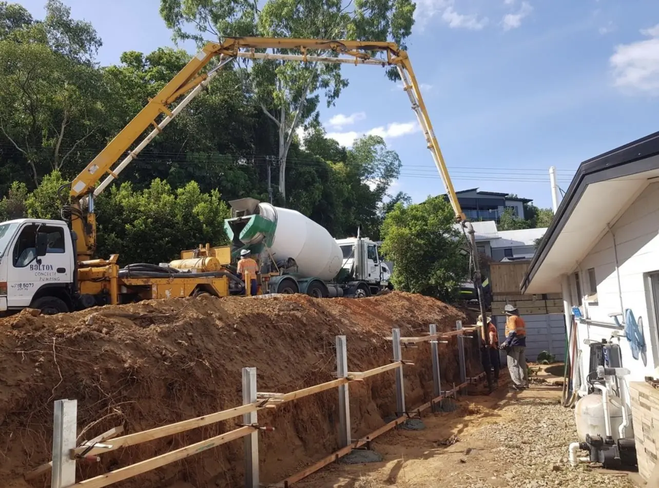 Crew pouring retaining wall footings with a concrete pump
