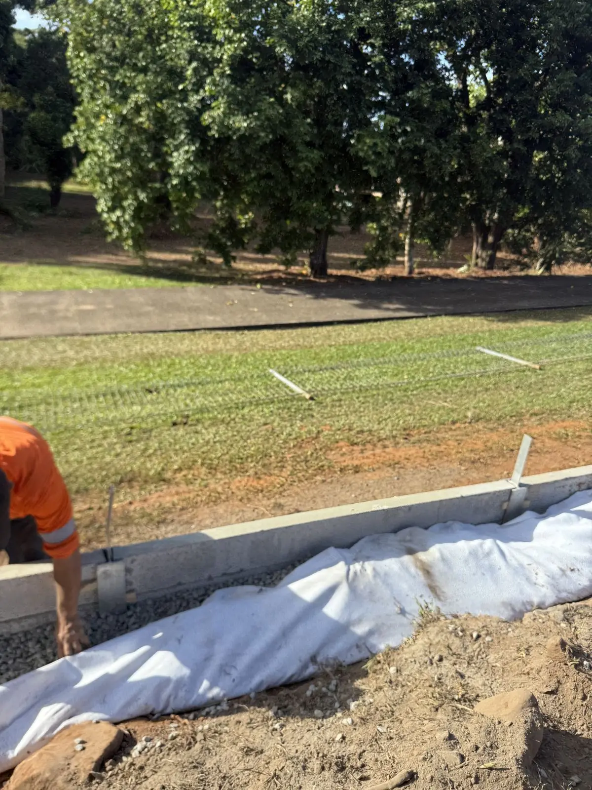 Geofabric-wrapped drainage being laid behind a new wall