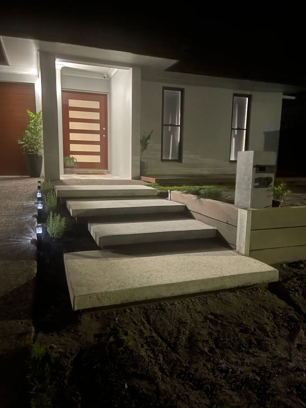 Floating concrete steps at a front entry at night