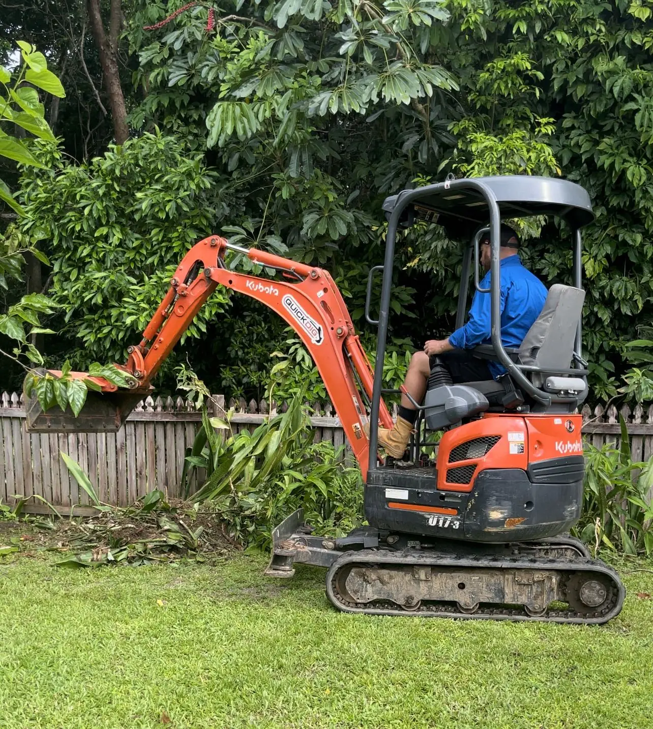 QuickDig mini excavator clearing a backyard garden bed