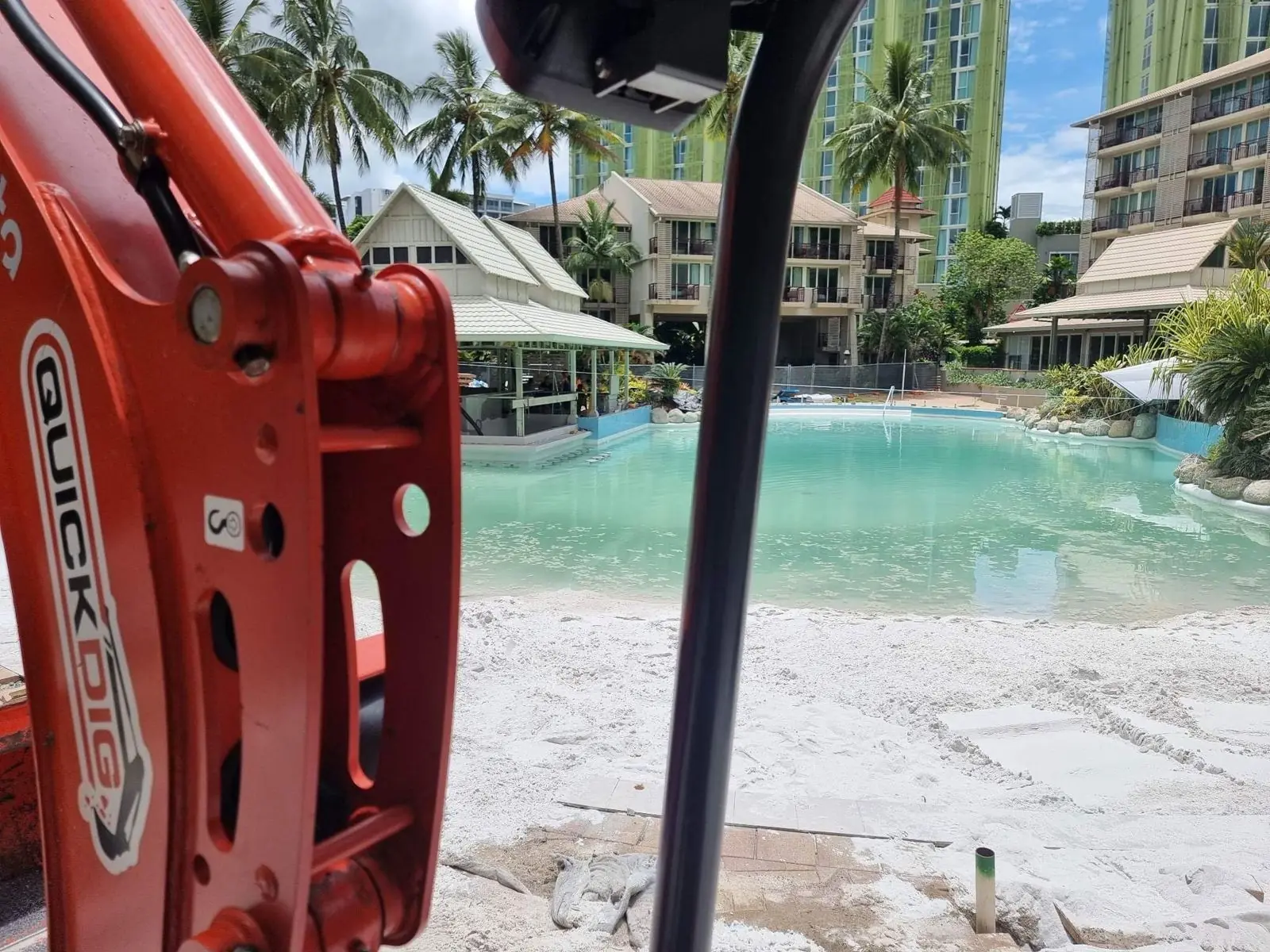 QuickDig excavator beside a Cairns resort lagoon pool