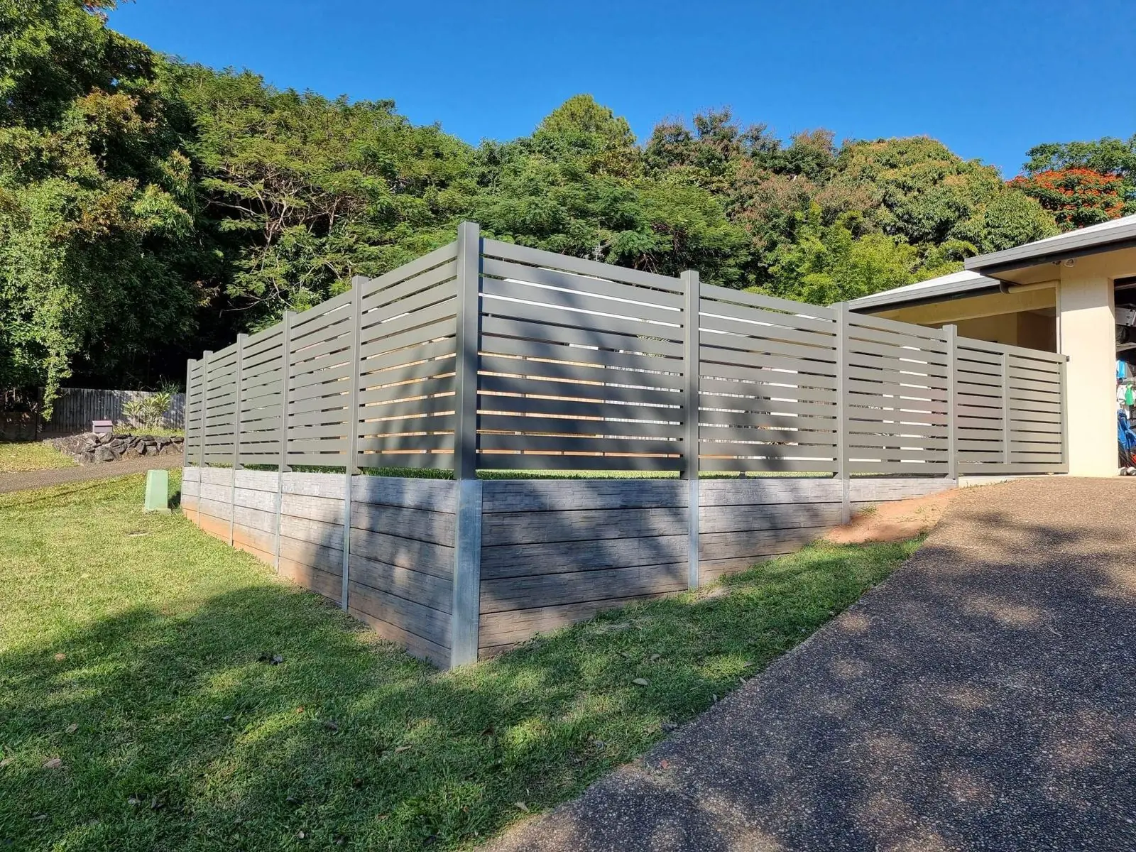 Aluminium slat fence on a stone-look concrete sleeper retaining wall